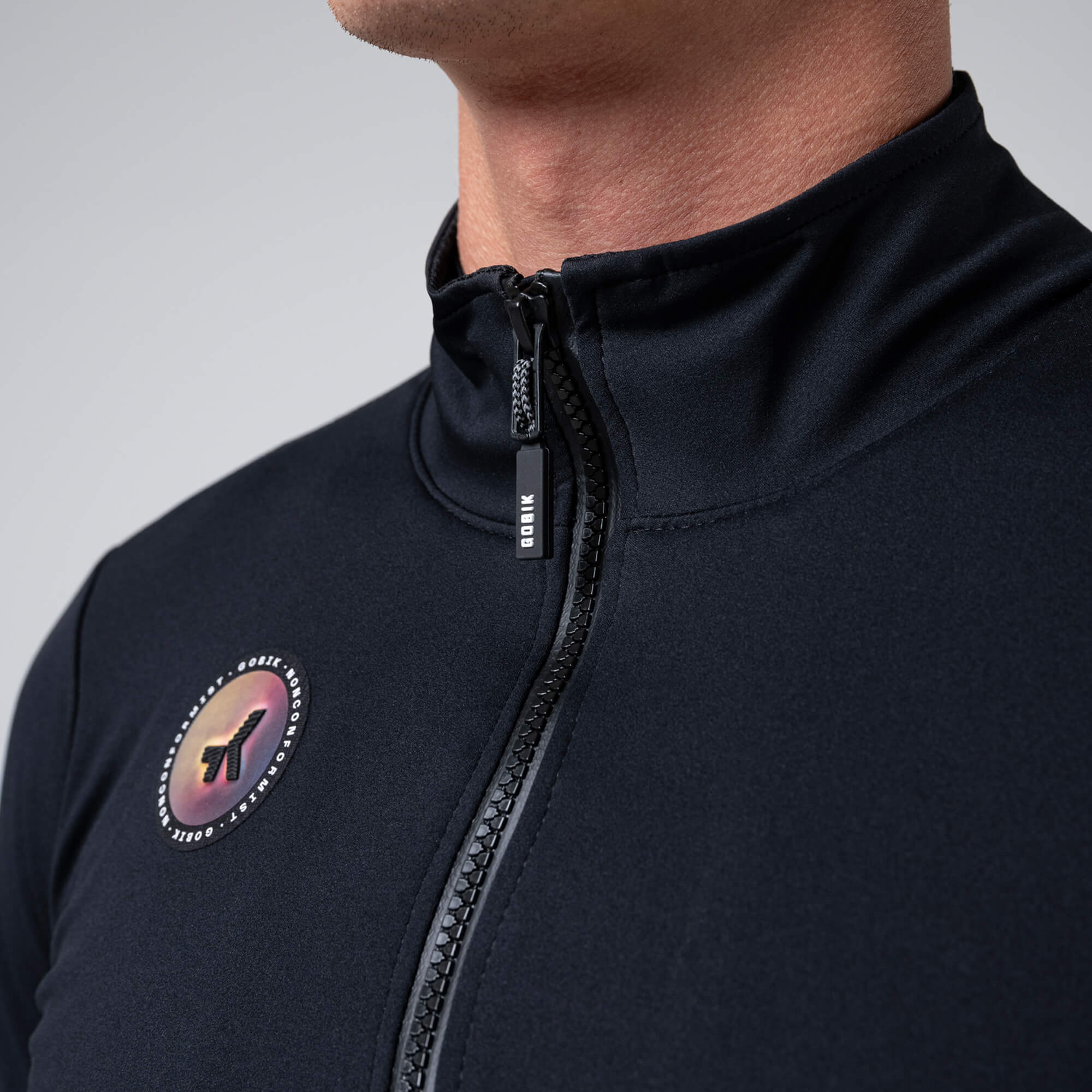 Close-up of GOBIK Armour 2.0 Thermal Jacket - Unisex showing front zipper and logo patch on black fabric