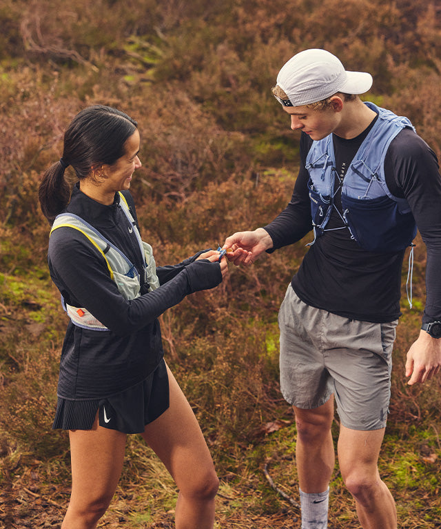 Two trail runners outdoors sharing an Amacx Energy Fruit Chew Piña during a break in nature