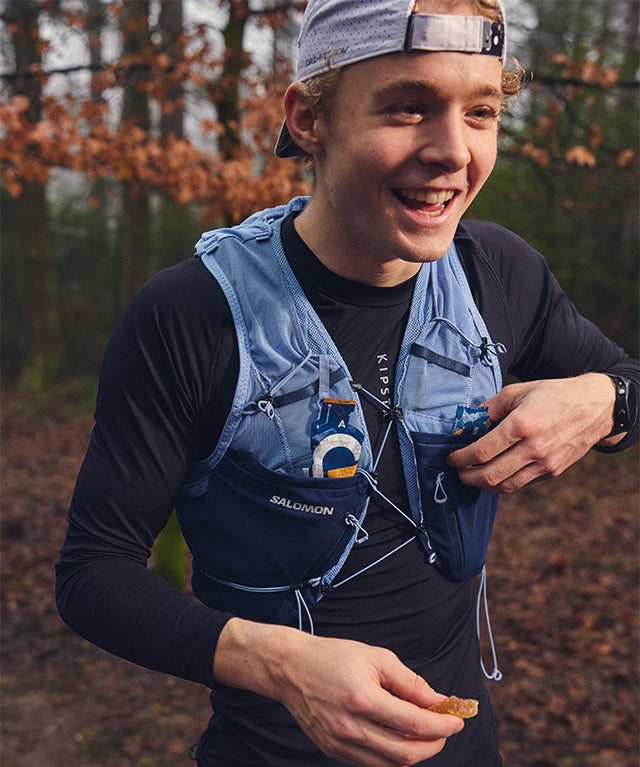 Active runner holding a gel with Drink Gel Raspberry | 12-pack visible in hydration vest pocket, gallery position 6 portrait