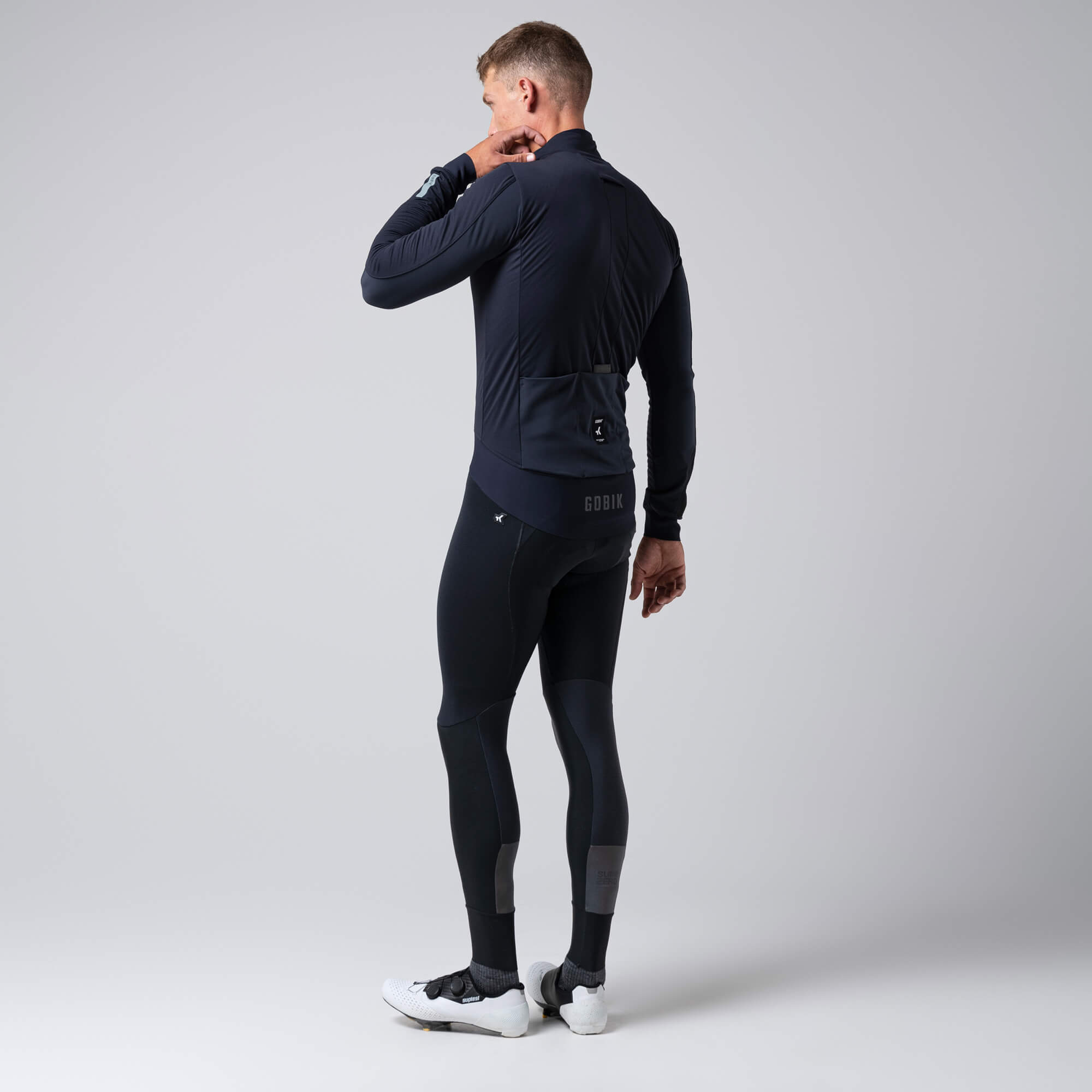 Man wearing GOBIK Armour 2.0 Thermal Jacket - Unisex shown from back with high collar and rear pockets against plain background