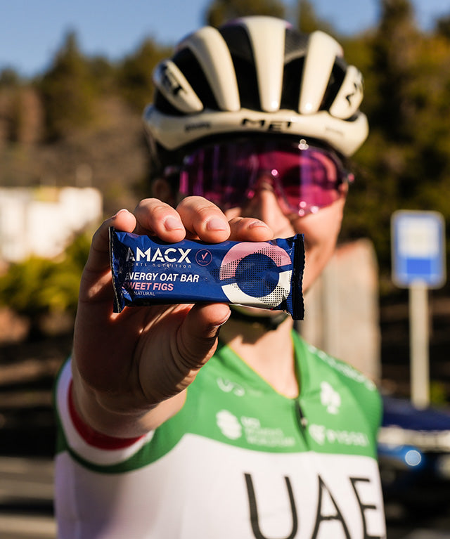Close-up of a cyclist holding an Amacx Energy Oat Bar Sweet Figs outdoors on a sunny day
