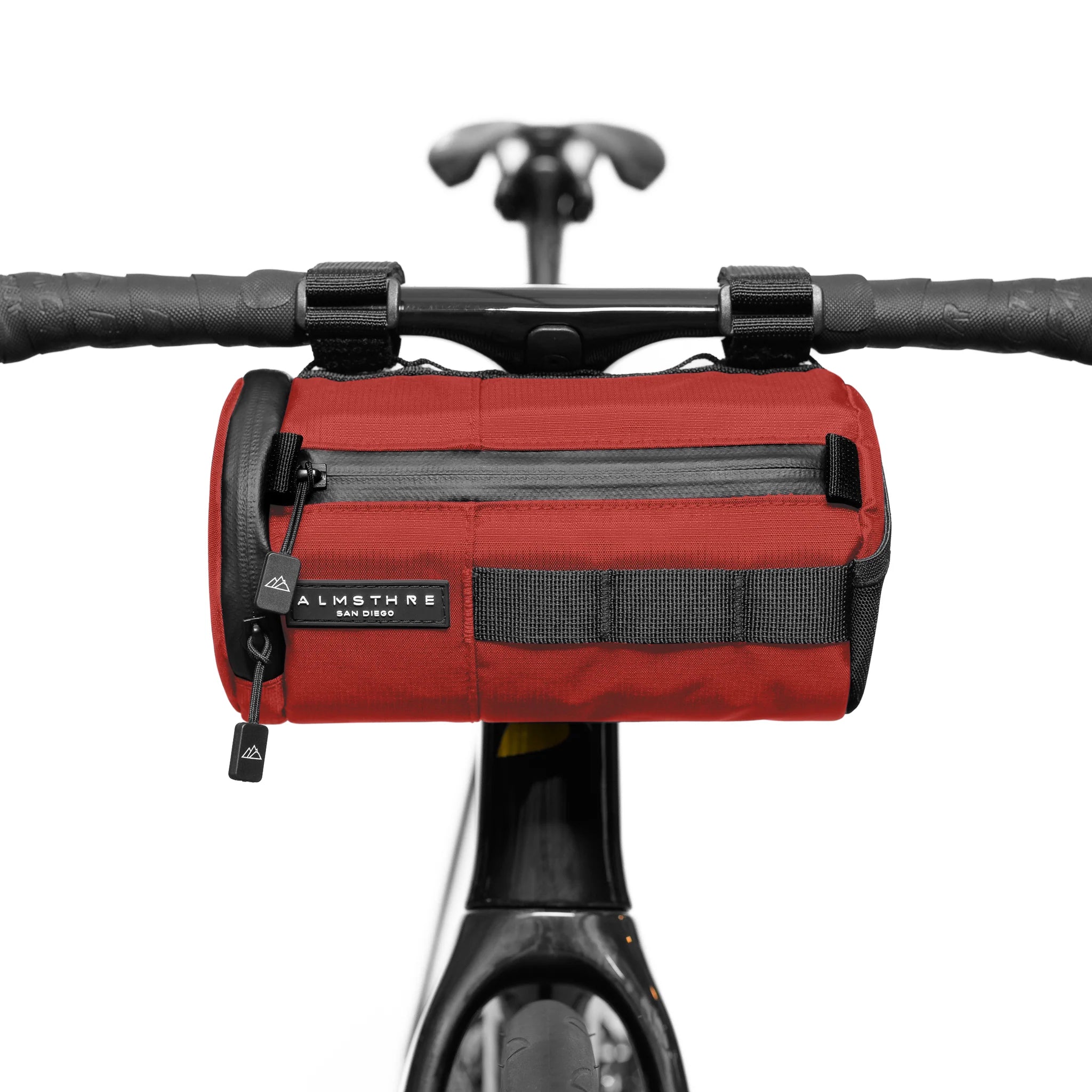 Red ALMSTHRE Signature Bar Bag mounted on bike handlebars showing front zipper pocket and sturdy attachment straps