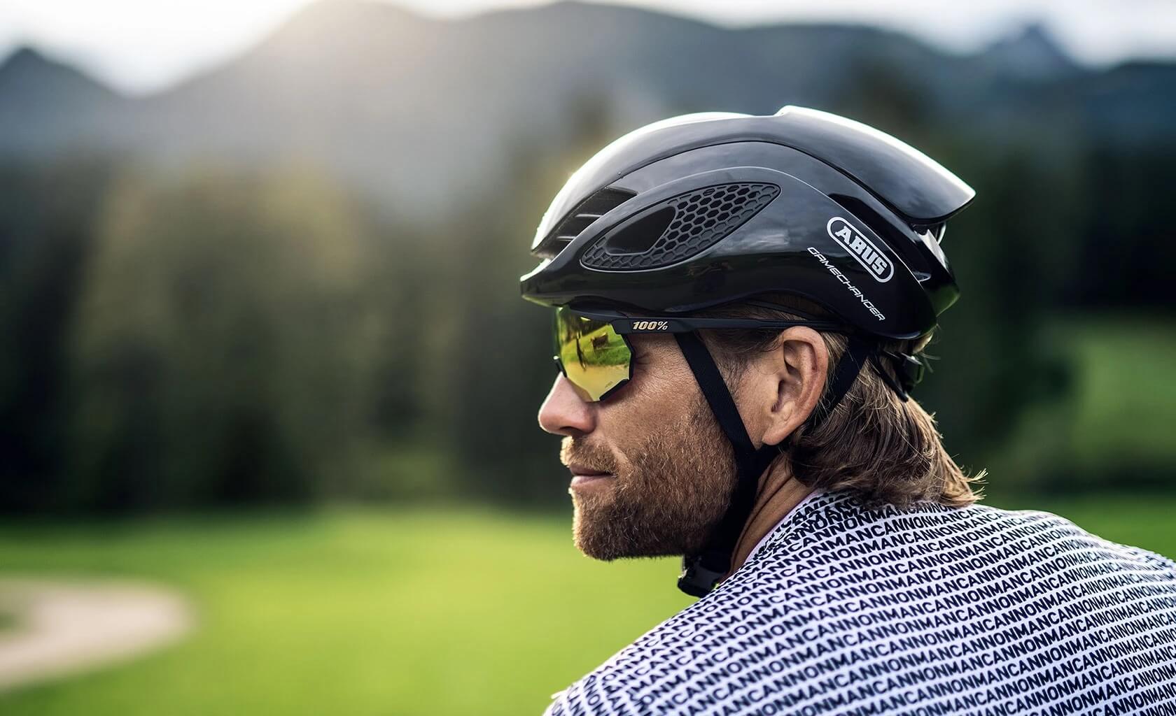 Man wearing ABUS GameChanger Helmet with aerodynamic shell and ventilation, looking outdoors against blurred natural background