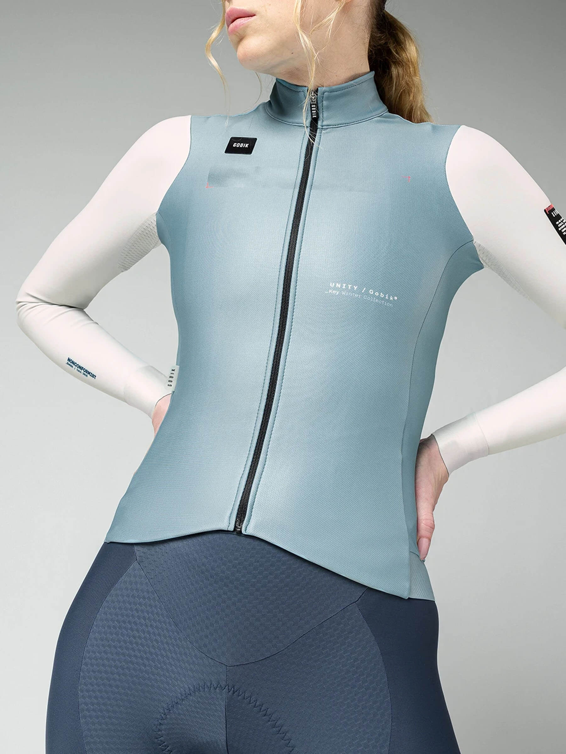 Woman wearing GOBIK Superhyder Long Sleeve Jersey - Women's in blue and white with front zipper and high collar against plain background